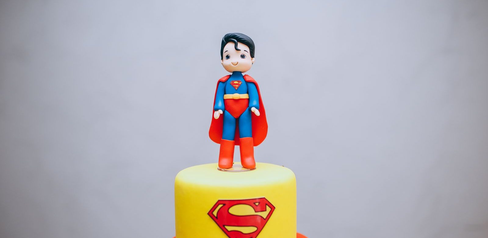 Gele taart met het Superman-logo erop en een klein Superman-figuurtje van fondant bovenop