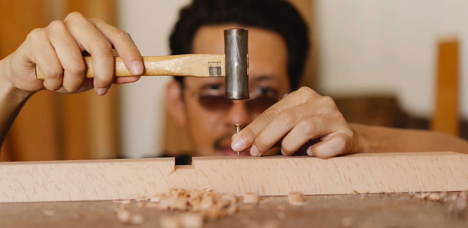 Een timmerman slaat een spijker in hout
