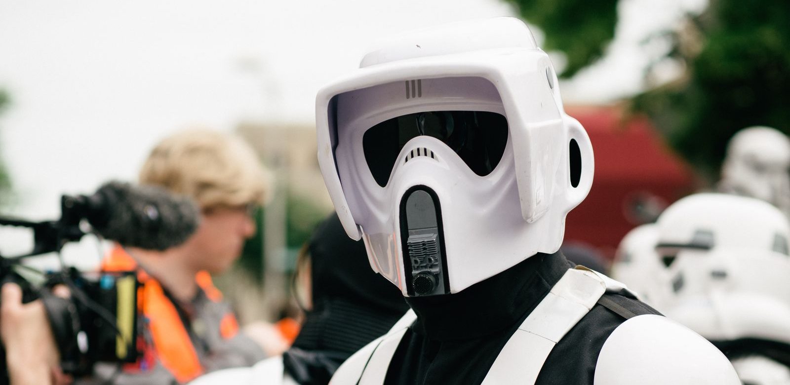 Iemand in een wit scout trooper-pak uit Star Wars op een evenement buiten, met een cameraman op de achtergrond