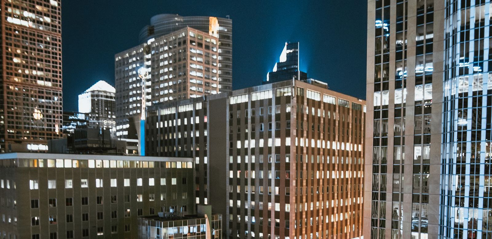 Iemand in een Spider-Man-pak op de rand van een dak boven de verlichte stad