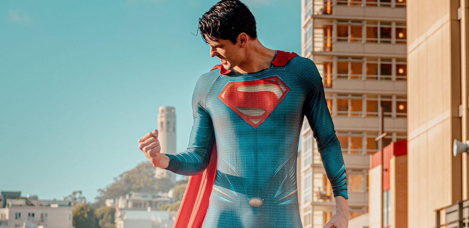 Een Superman-figuur klimt langs een gebouw bij neonlicht