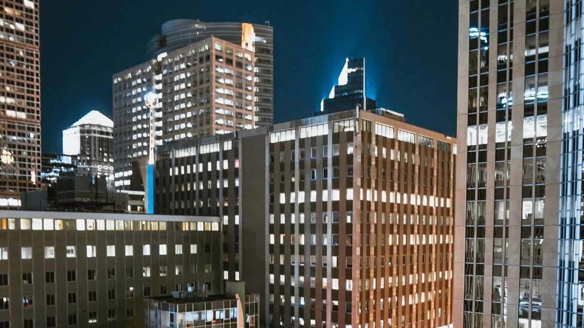 Iemand in een Spider-Man-pak op de rand van een dak boven de verlichte stad